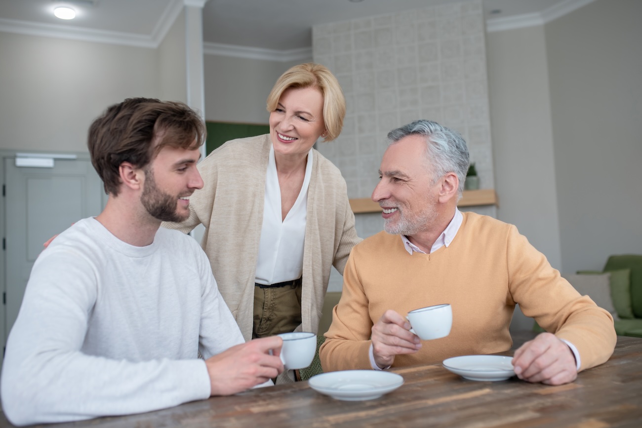 Smiling parents having a discussion at the kitchen table with their son.