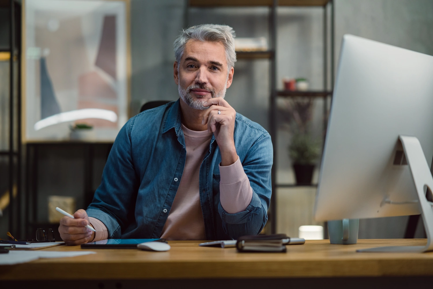Man sitting at a desk working with a tablet and digital pencil.